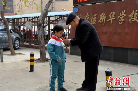 图为张善德为小学生整理红领巾。郝学娟 摄