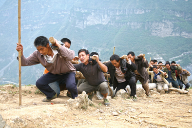 ▲凉山州甘洛县乌史大桥乡，正在建设家乡的当地群众奋力抬电线杆，向山顶的二坪村攀登。
