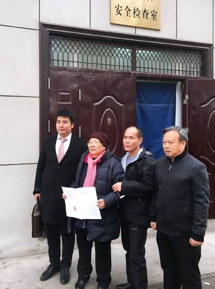 　　2017年11月30日，周远拿到无罪判决书后走出法院。右起：伊宁三中老校长龙富初、周远、周母李璧贞、代理律师刘征。摄影/杨宝璐