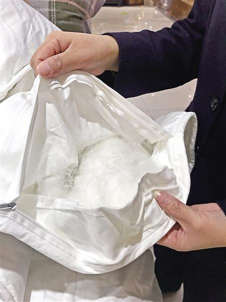 　销售人员在展示蚕丝被里的蚕丝 记者 韦玥 摄
