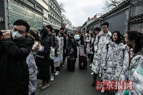 一位家长推着行李从考生队伍间穿过。