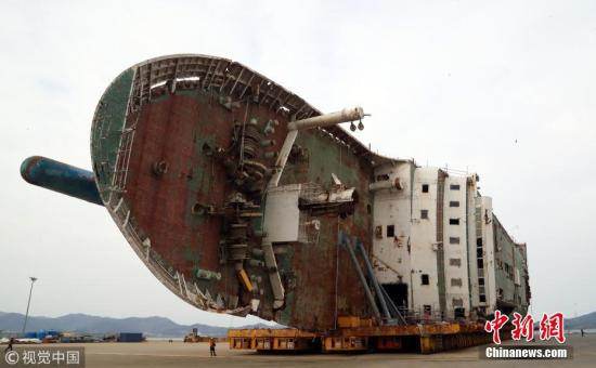 　　资料图：当地时间2018年2月21日，作业人员在韩国全罗南道木浦新港准备将“世越”号移动至模件运输车（MT）上。当天将“世越”号打横移动后，工作人员准备于5月31日扶正船体。 图片来源：视觉中国