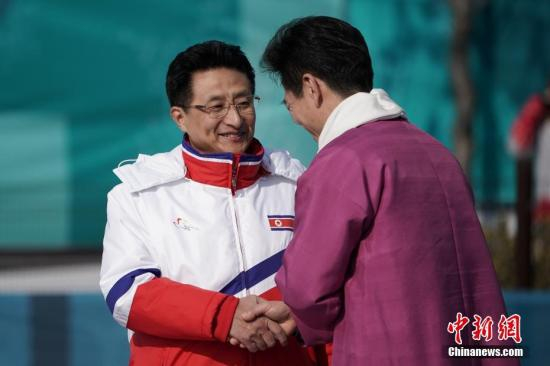 朝鲜代表团团长、朝鲜体育部副部长元吉宇（左）与江陵奥运村村长金琪勋握手。中新社记者 崔楠 摄