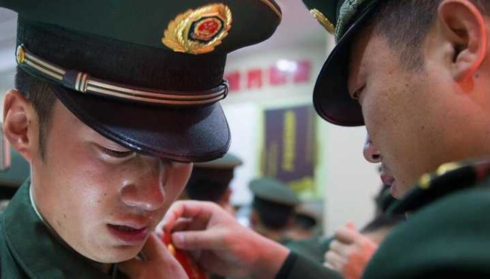 2015年11月30日，天安门国旗护卫队退伍老兵 ，国旗护卫队队长徐文为魏凯（左）摘下肩章、领花和帽徽（11月30日摄）。新华社发 栗世民 摄