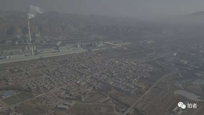 　　△ 2017年12月8日，记者用无人机从空中俯拍的中铝兰州分公司两个厂区和周边村落的关系。有的村民房屋离厂区围墙不过十几米。其周边主要分布的是平安镇村落，涉及约2万居民。