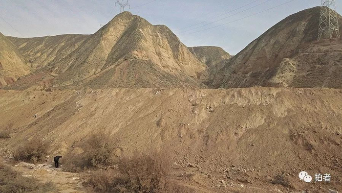 　　△ 2017年12月9日，记者拍摄的相似角度图片，平安镇岗子村撒拉沟大斜坡上的夹杂有大量废阴极炭块的电解铝固废看不见了，不过，凑近看，仍然有很多废阴极炭块暴露在覆土外，土坡长约100米，高6米以上。土坡上被推平成一个巨大平台。“垃圾场”承包人曲学顺表示，大概在2个月前，他安排施工，动用了挖机和推土机，推土掩埋了一些废阴极炭块及其它固废，包括生活垃圾。