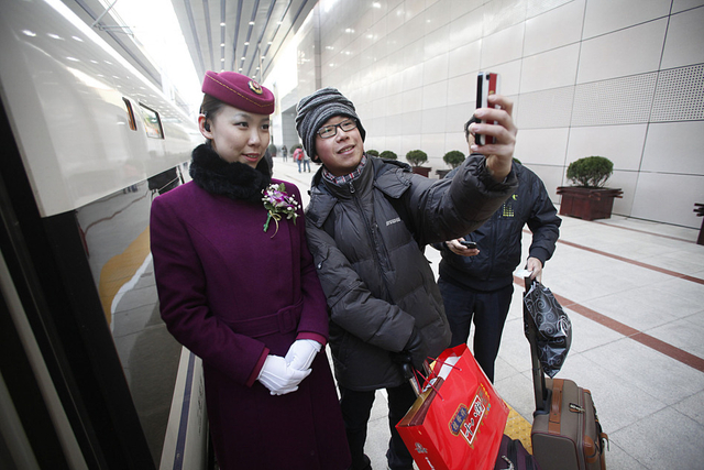 乘坐前往广州的G801次高铁的旅客和服务员合影