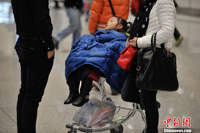 小女孩盖着父亲的衣服睡在行李推车上