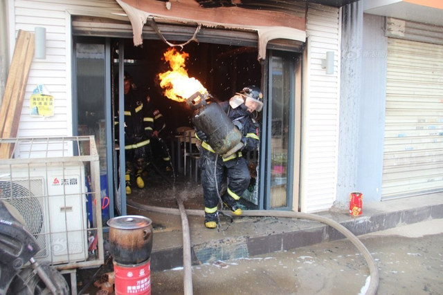 消防员抱煤气罐冲出火场