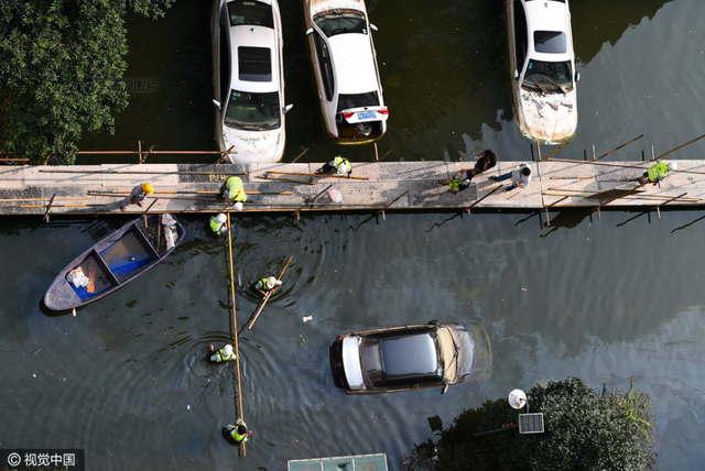 武汉小区积水9天未退 工人搭栈桥供居民出入