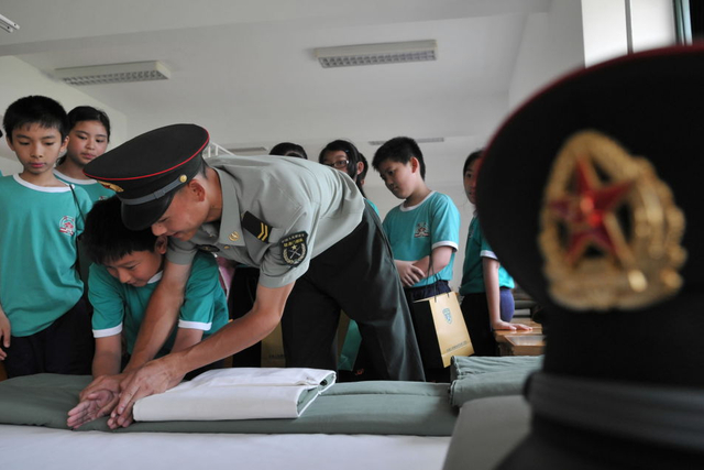 一名澳门小学生在驻澳门部队士兵指导下叠被子